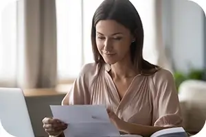 Woman sitting at her table reviewing dental plan benefits.