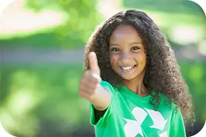 Young girl in green earth day shirt giving thumbs up.