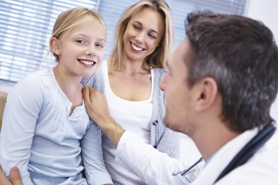 Dentist congratulating a mother and daughter on a great checkup.