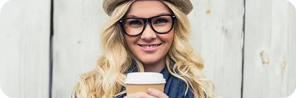 Smiling young woman in glasses with a cup of tea.