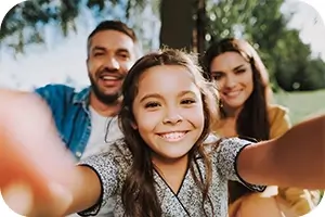 Young girl taking a smiling selfie with her parents.
